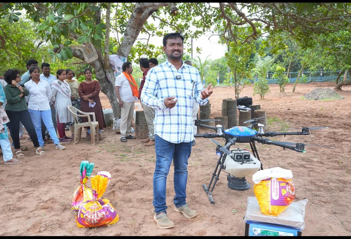 A trainer explaining an agricultural drone to a group of farmers and visitors